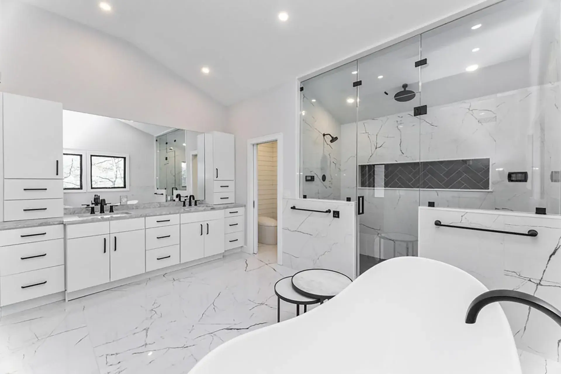 Bathroom with marble slab walls, a double vanity and a freestanding tub