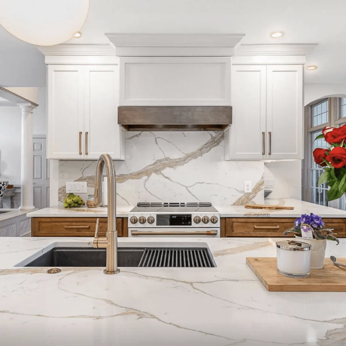 Full slab Calacatta Lavish backsplash behind a range with pot filler