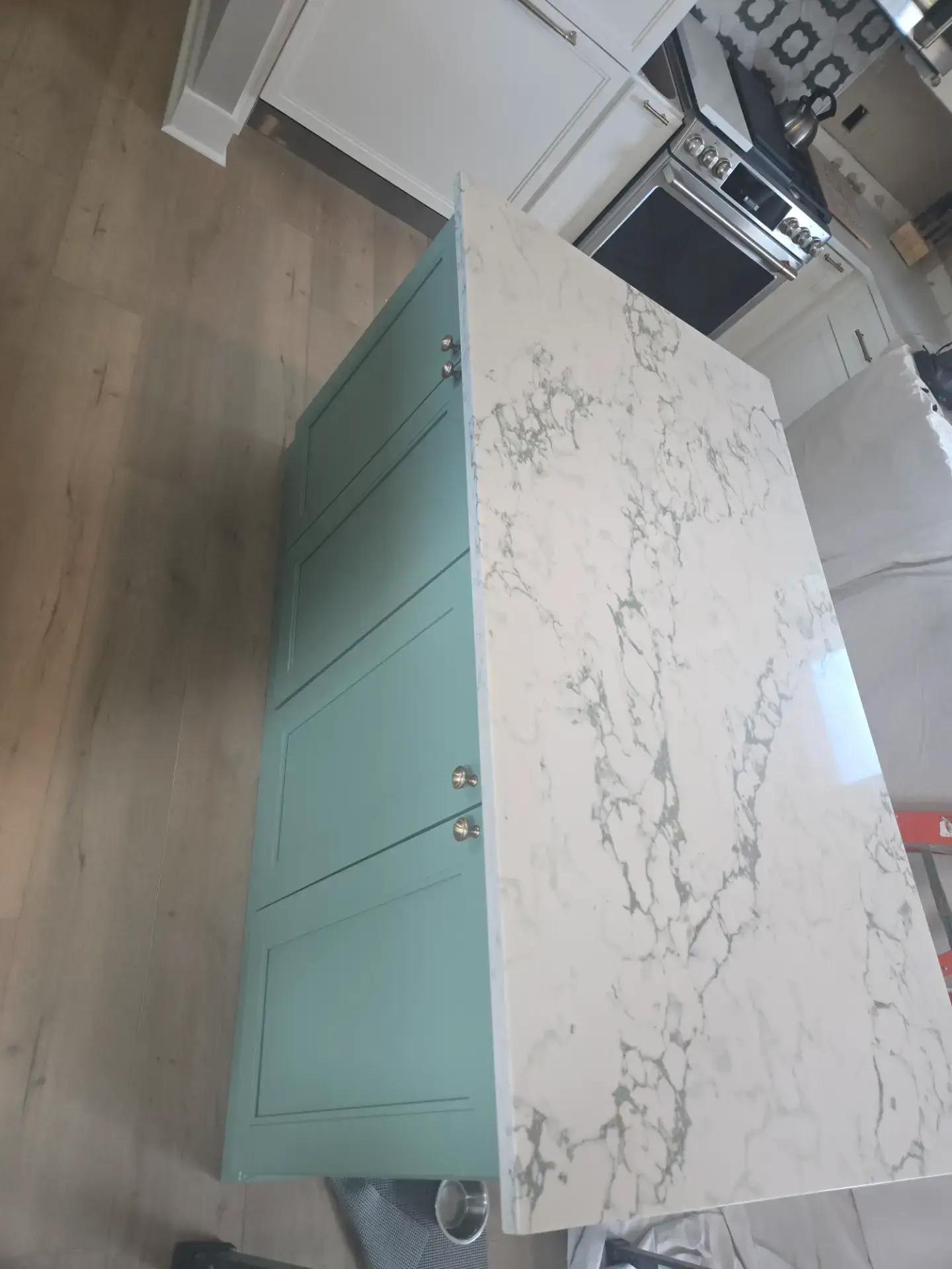 Mitred edge of a veined stone slab on a teal cabinet
