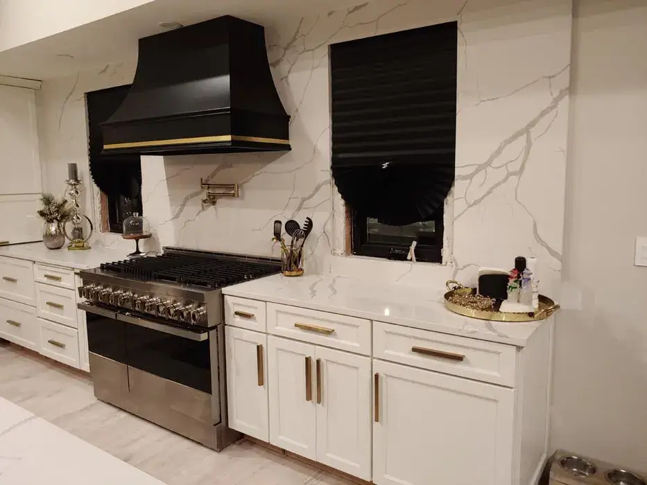 Full height marble look slab behind a range under a black hood