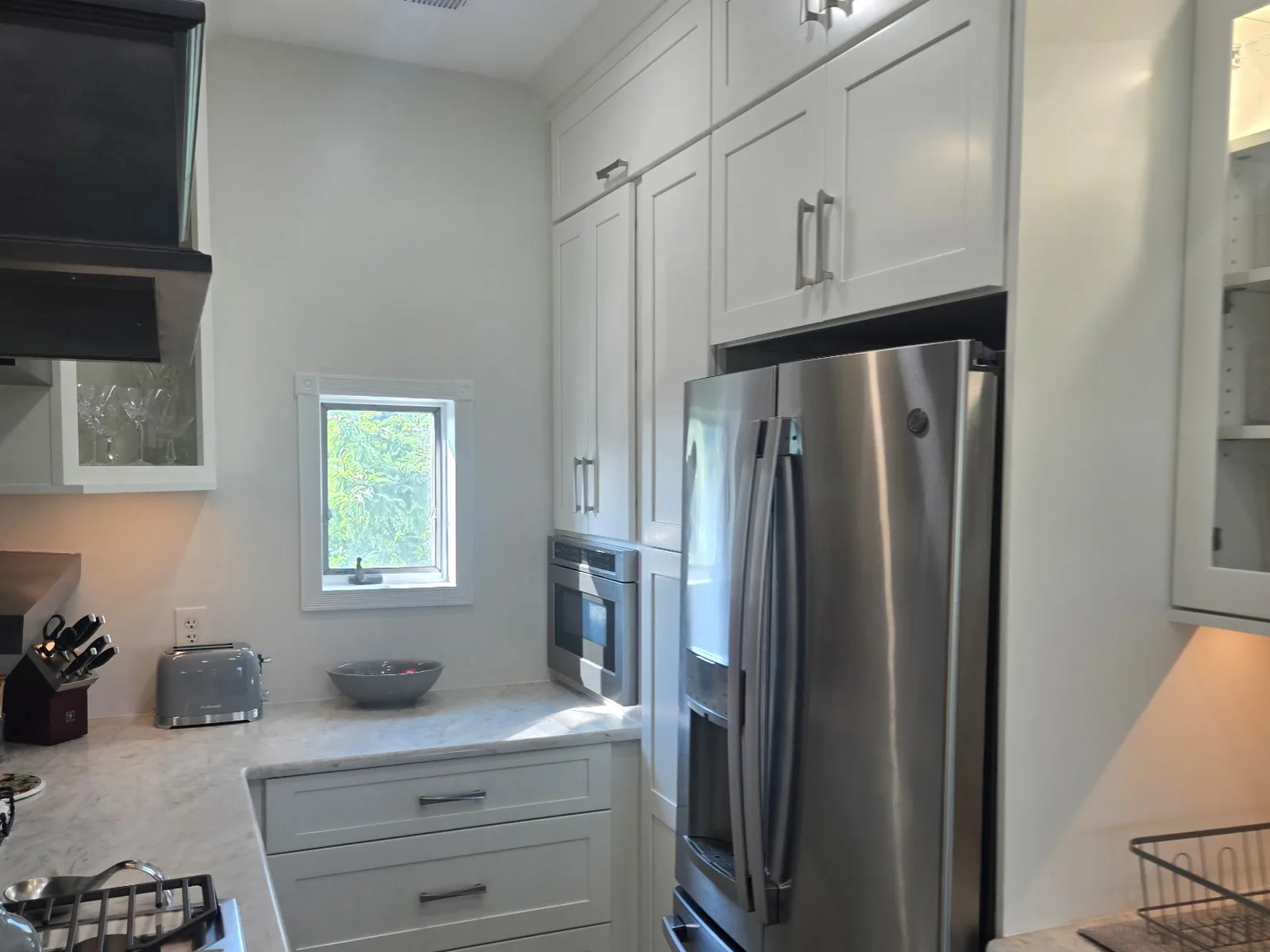 Light veined stone countertop continuing around a kitchen corner beneath a window