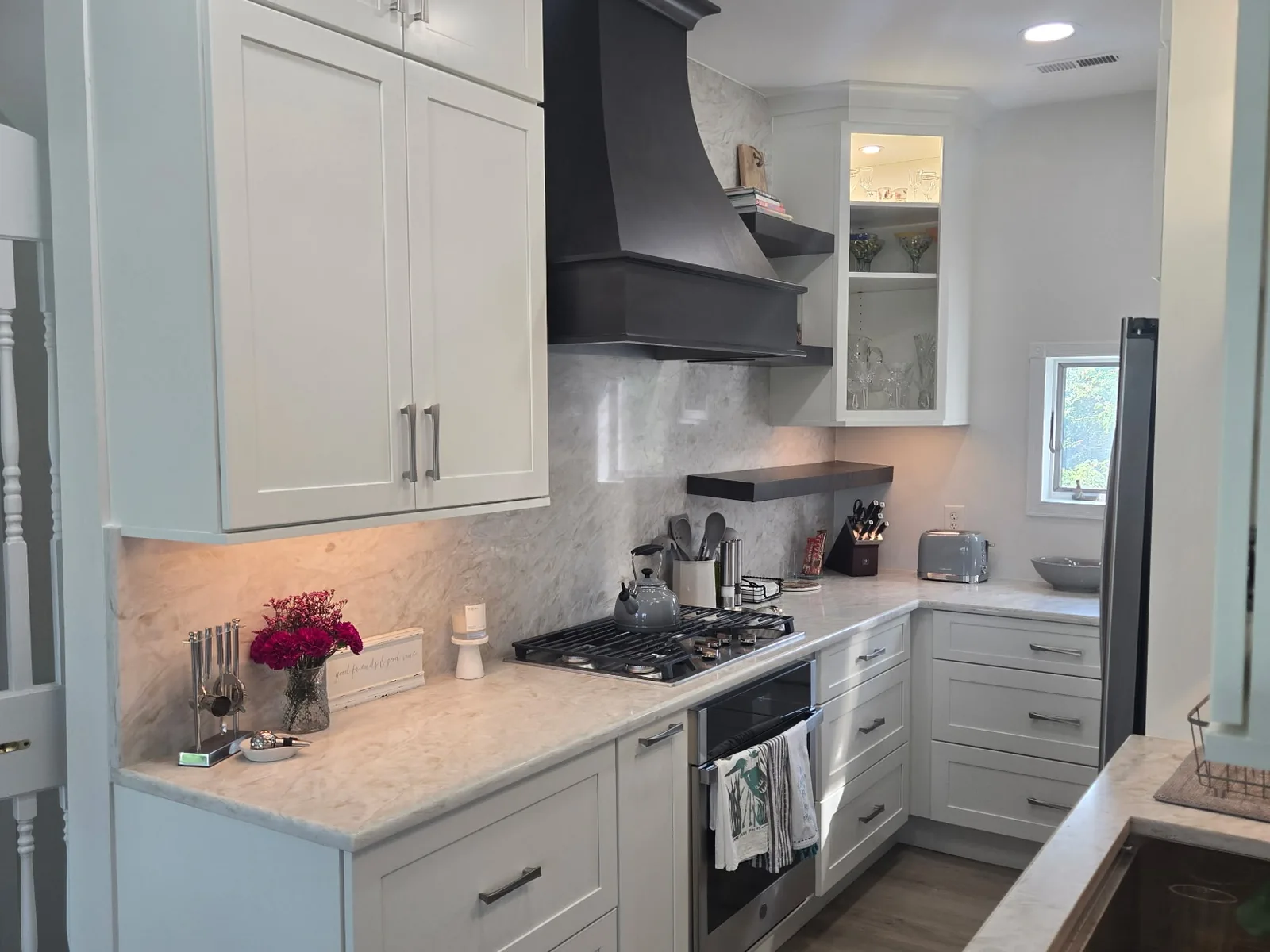 Full height stone slab backsplash running behind a range under a dark hood