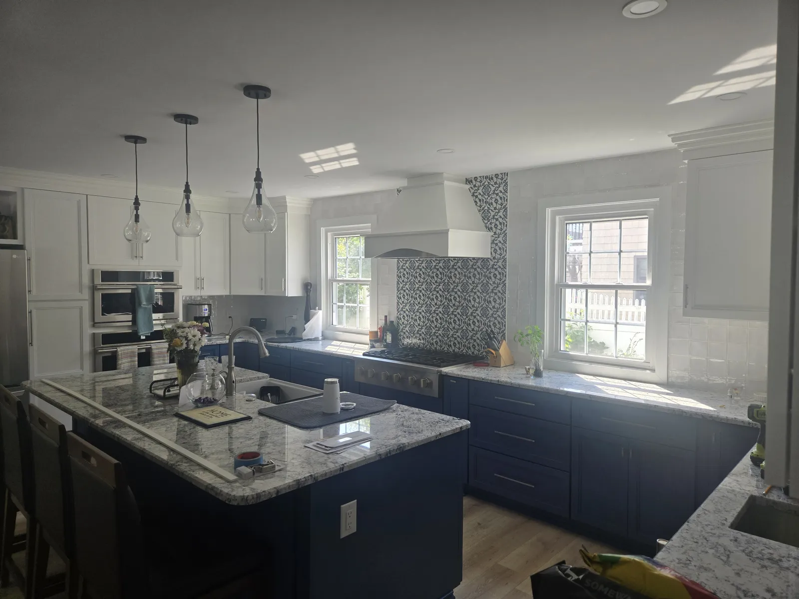 Speckled granite island top on navy cabinets with pendant lights
