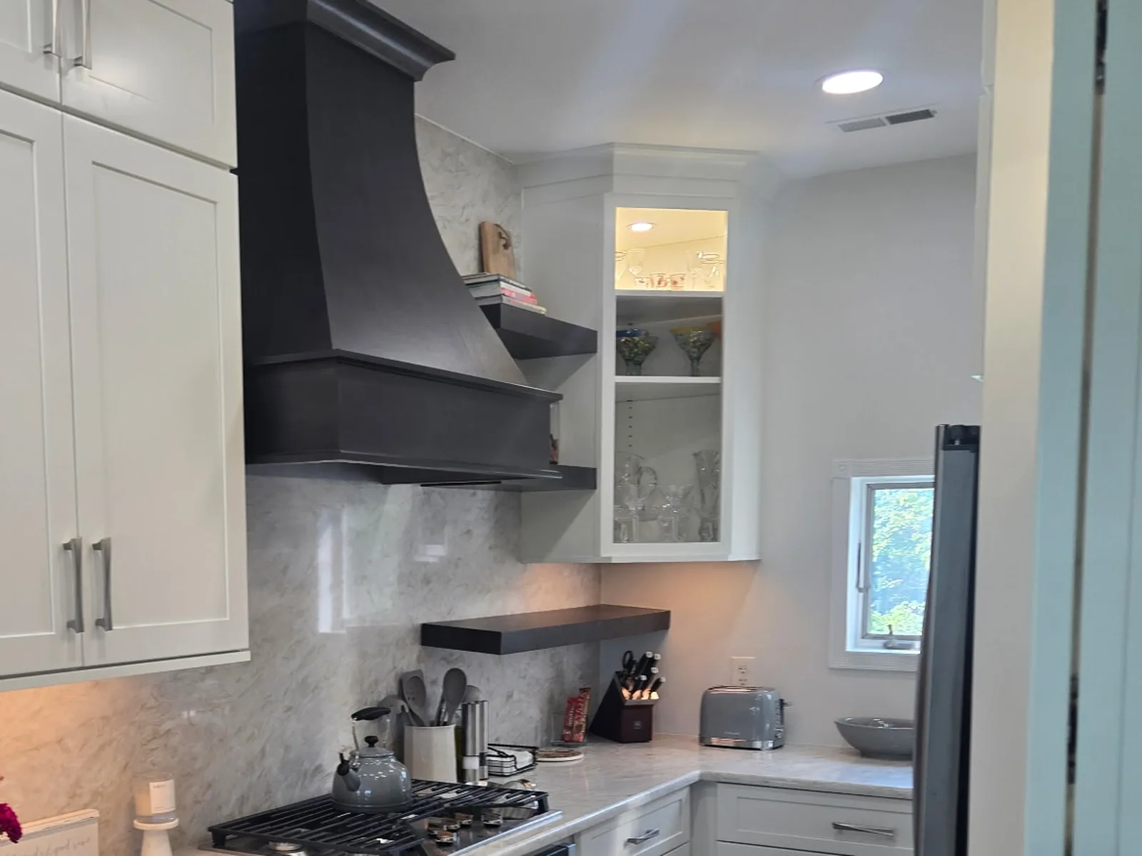 Stone counter run beside a range with a peninsula counter and undermount sink in the foreground