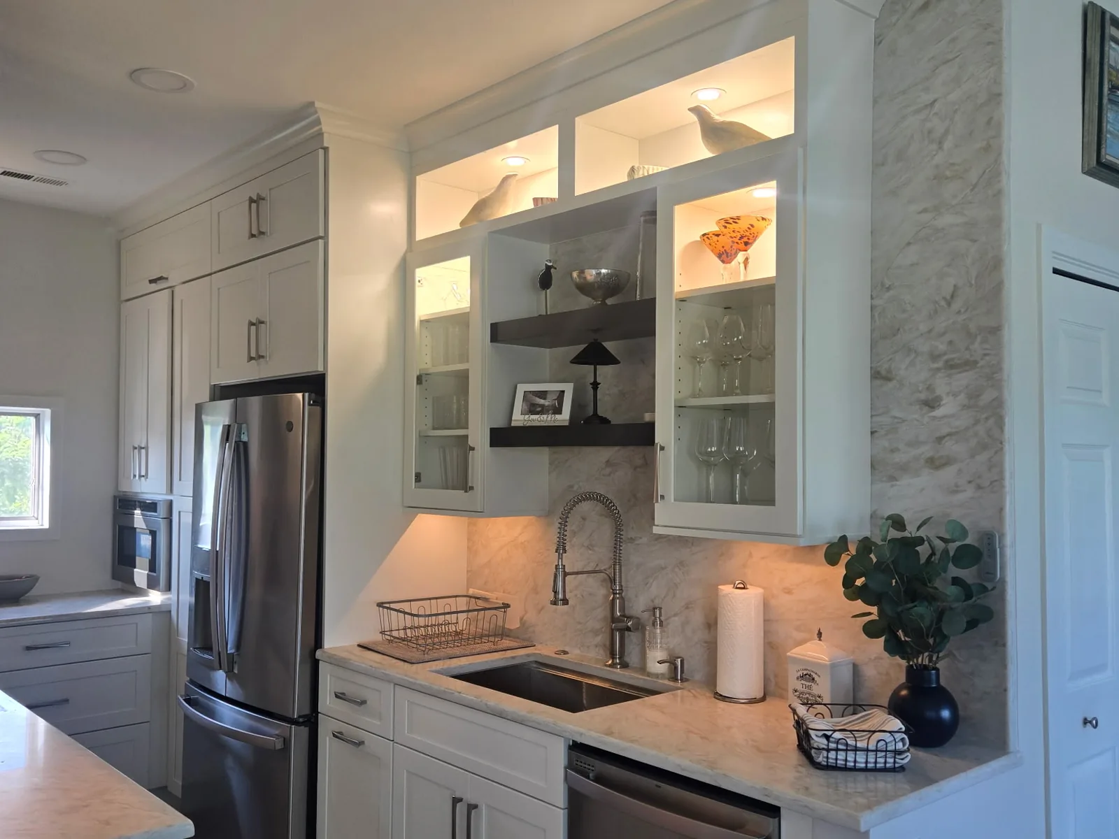 Stone countertop and matching slab backsplash at a prep sink with a clad column beside it