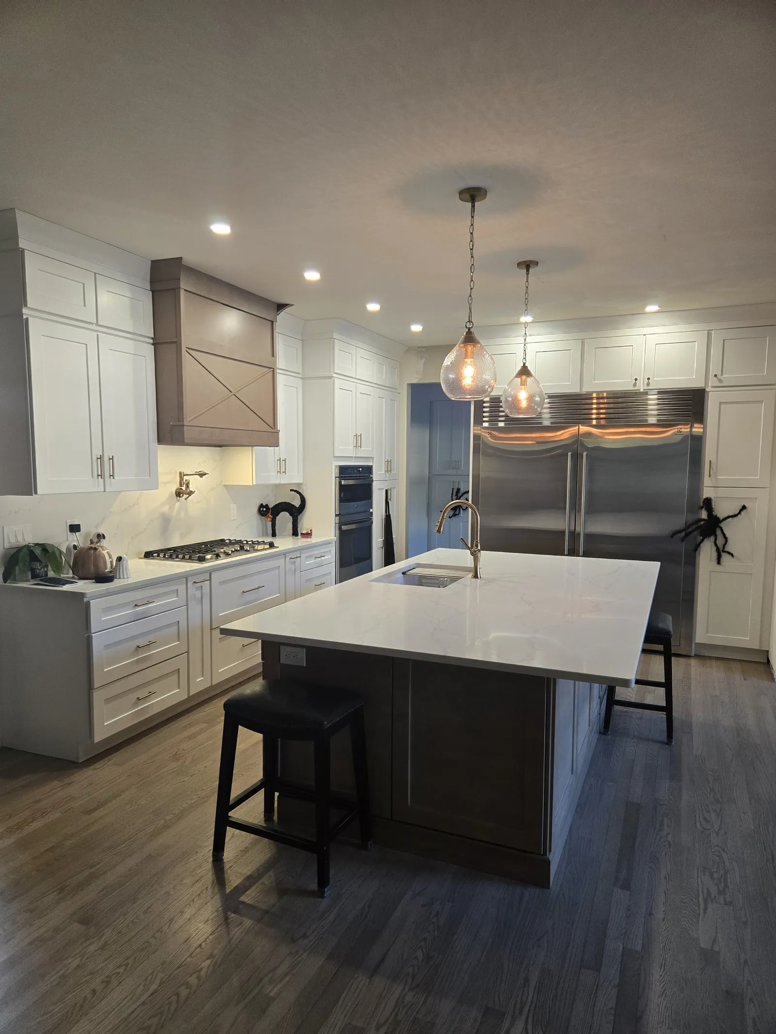 White kitchen with a stone topped wood island and pendants